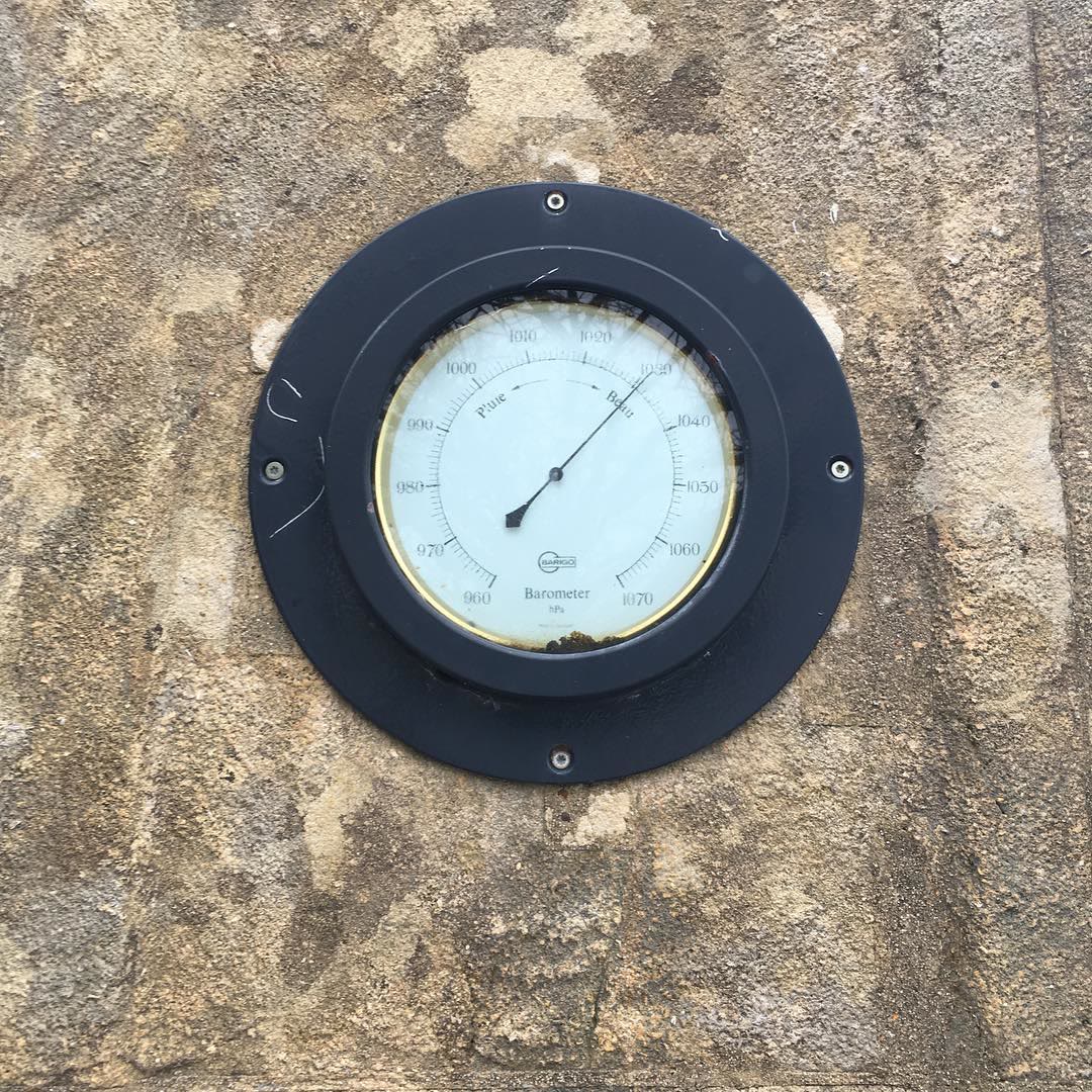 A round barometer set into a stone wall