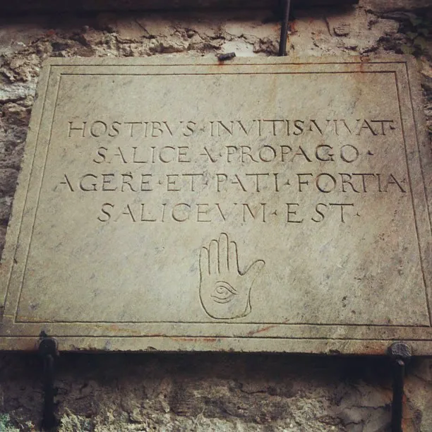A stone plaque carved with a Latin inscription and a hand with an eye in the palm