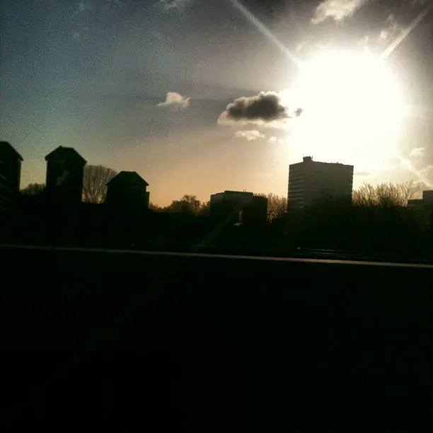 Morning sun breaking over low clouds and a row of apartment blocks in silhouette