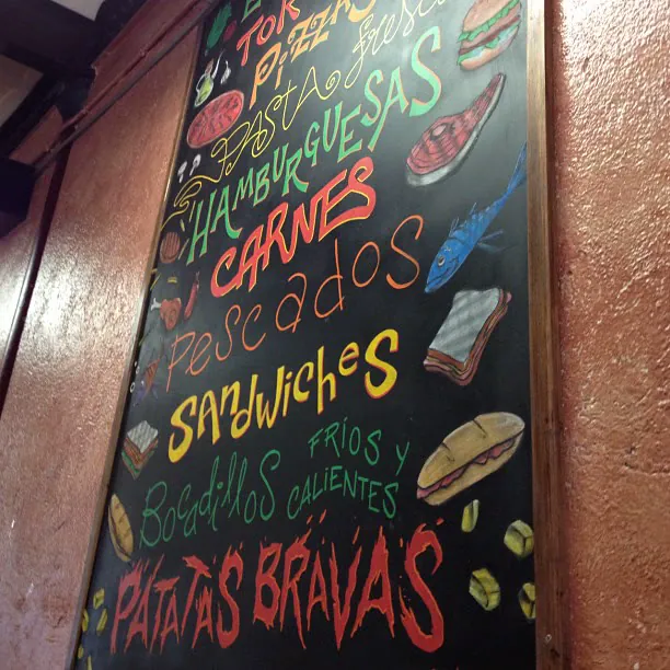 Una pizarra de menú con letras de colores: hamburguesas, carnes, pescados, sándwiches y patatas bravas