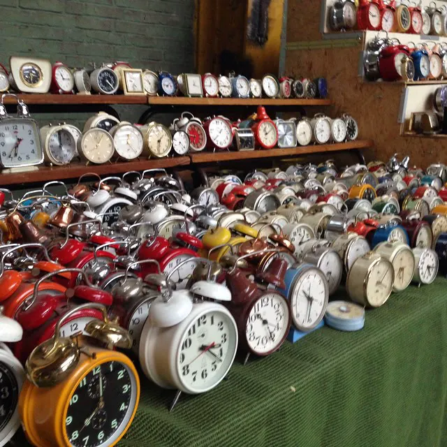 A market stall covered in dozens of old wind-up alarm clocks