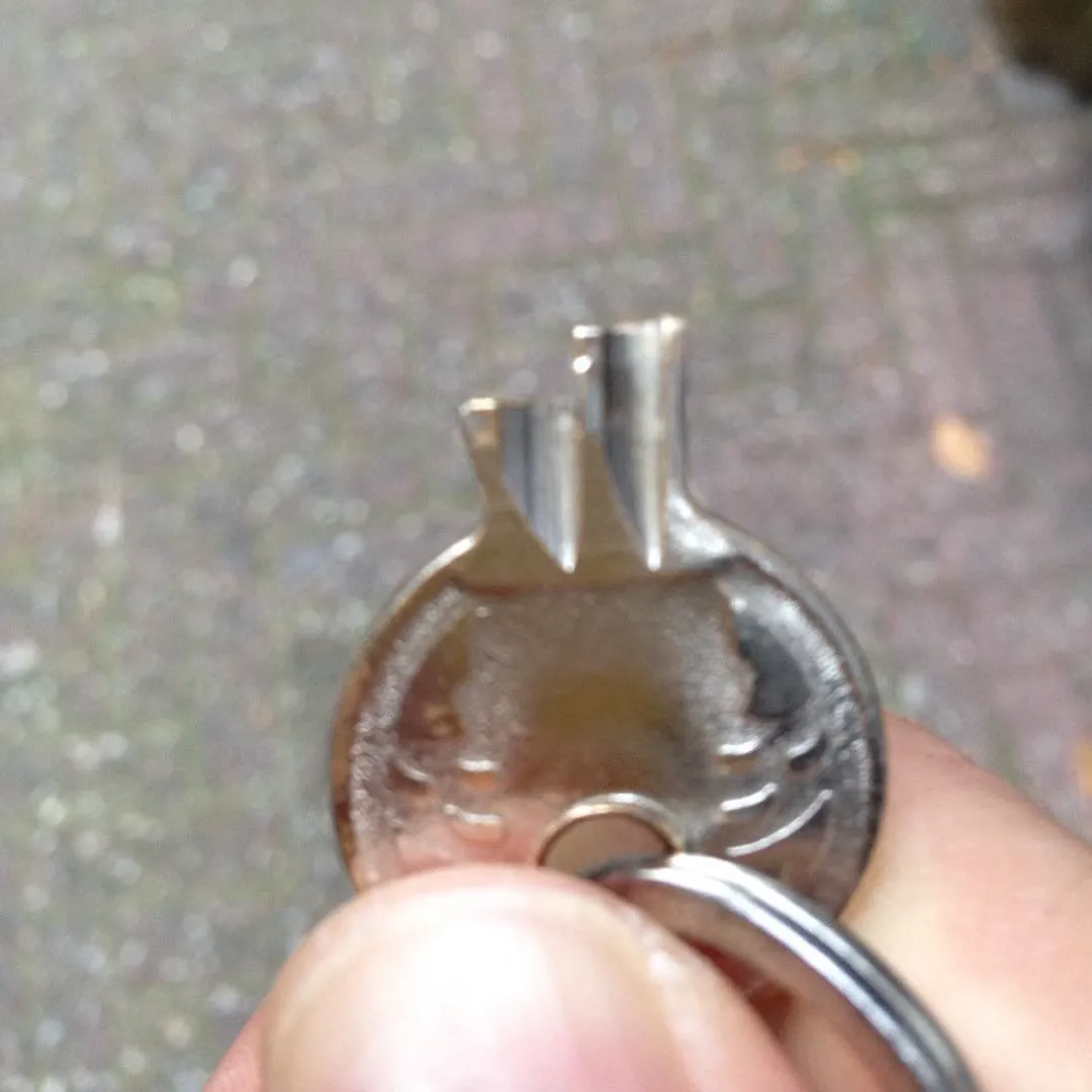 A hand holding a bicycle key with a broken bit