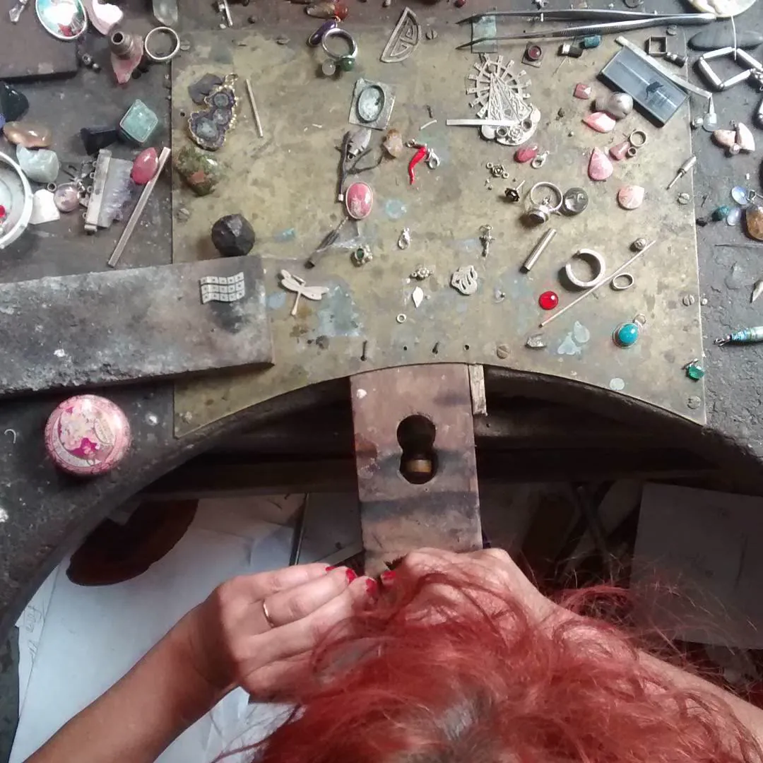 A jeweller's workbench scattered with tools and tiny pieces, seen from above