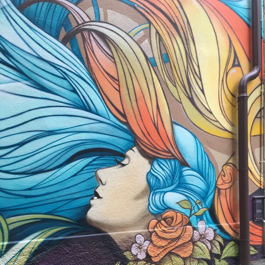 Street art in Neuchâtel: a woman's profile in a sweep of blue and orange hair