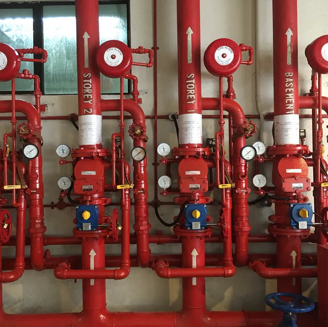 Red sprinkler pipes and valves labelled by storey, in Singapore