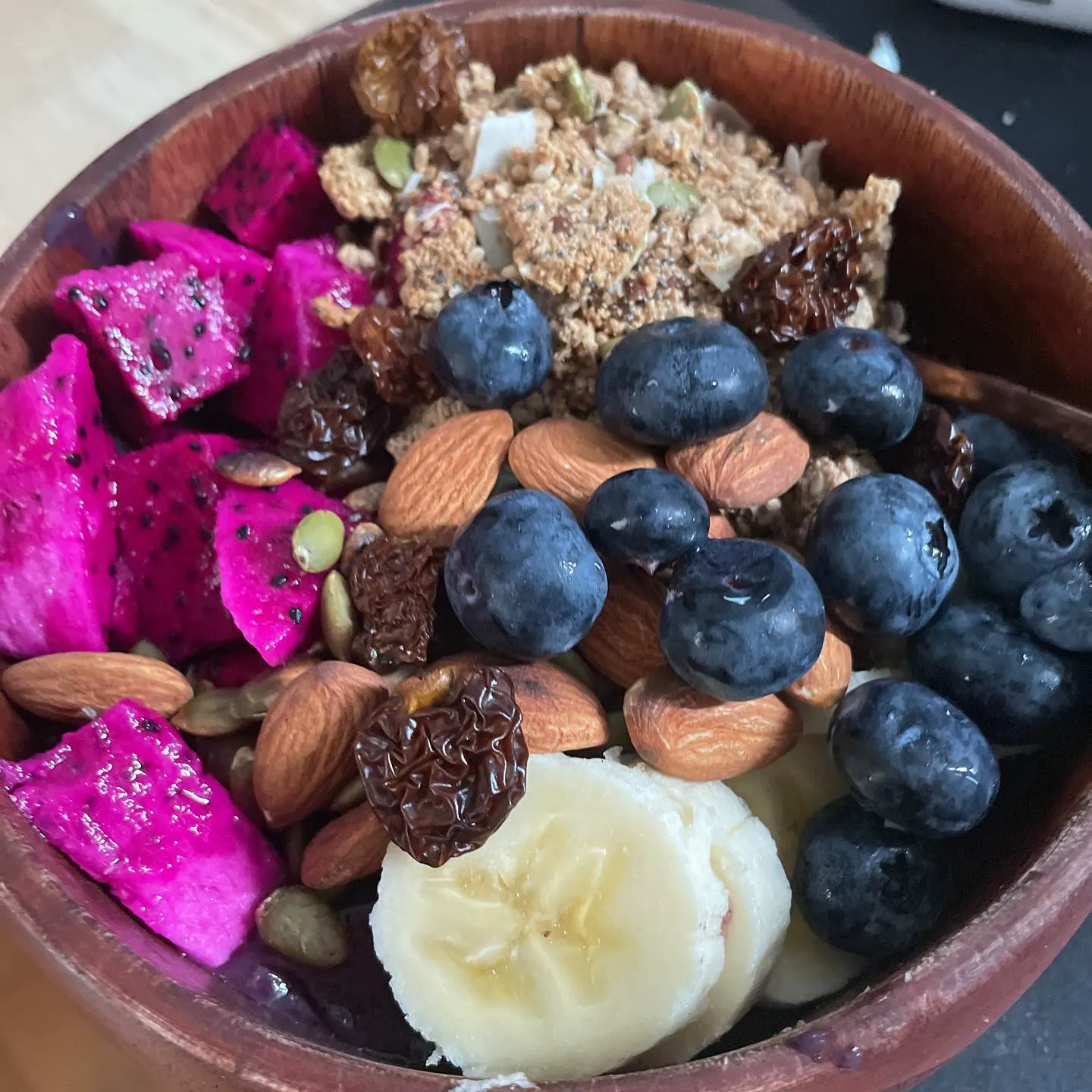 A breakfast bowl of dragon fruit, blueberries, banana, almonds and granola
