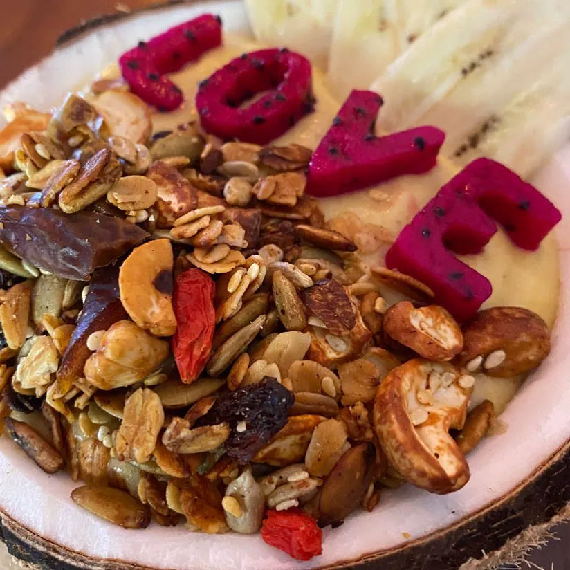 Granola, nuts, seeds and dragon fruit letters spelling LOVE in a coconut shell